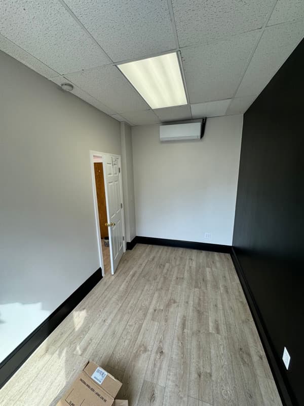 Commercial office with black ceiling, white walls, and wood accent wall in Boston, MA
