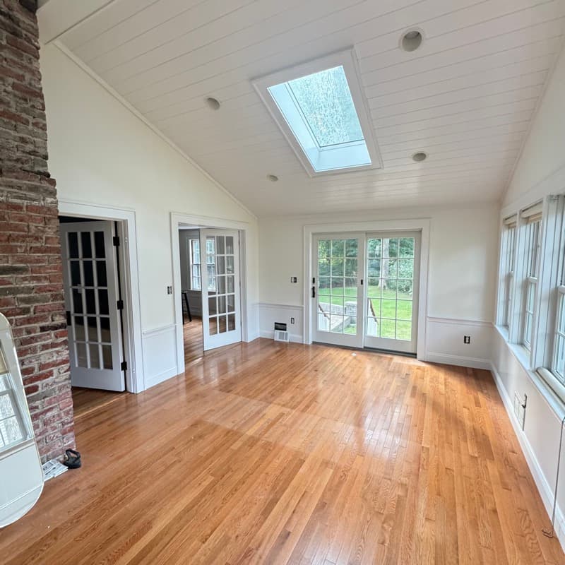 Sunroom with white shiplap ceiling, skylight, exposed brick, and wainscoting in Lynnfield, MA