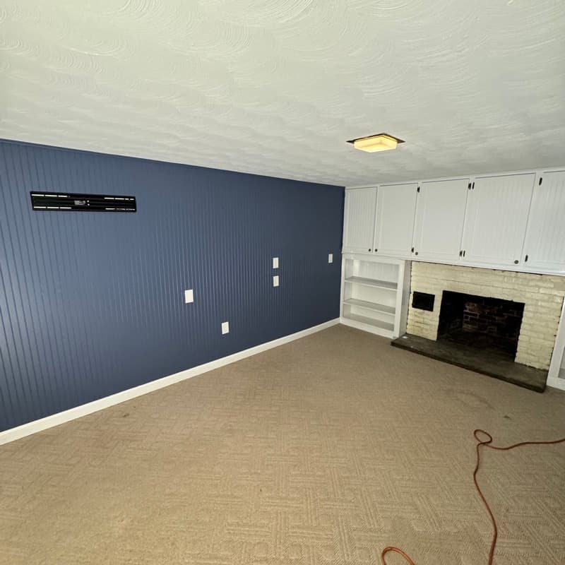 Basement with navy blue beadboard accent wall and white built-in cabinets in Lynnfield, MA